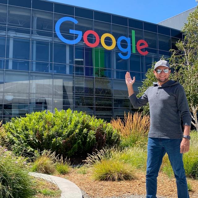 A man waves in front of the Google building.