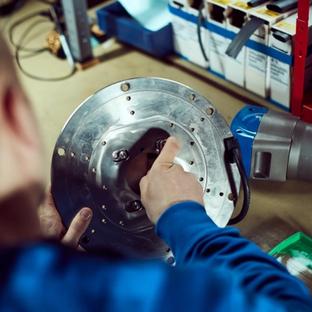 Person in a blue shirt assembling a circular metal component.