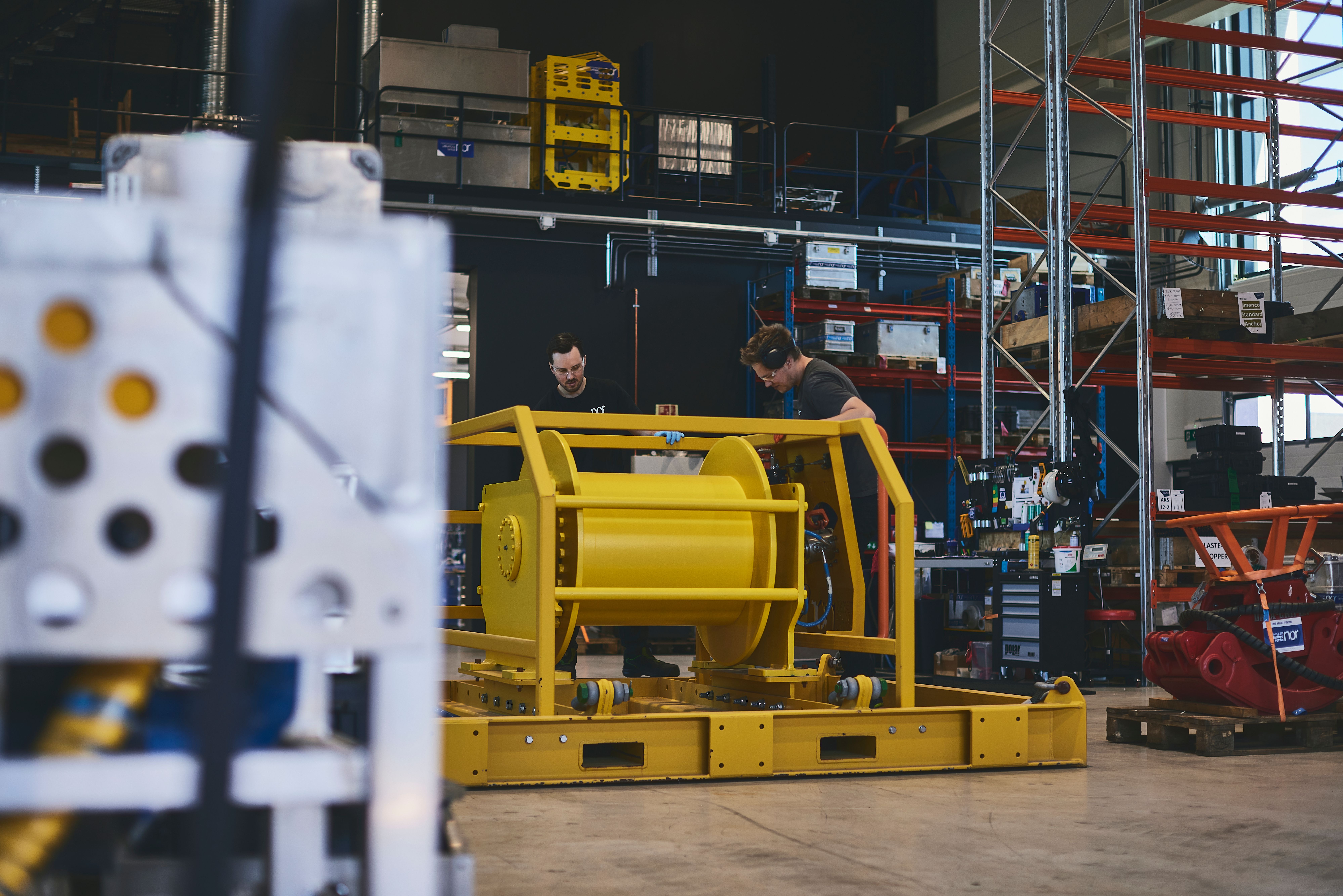 Two workers assembling a large yellow industrial machine in a workshop.