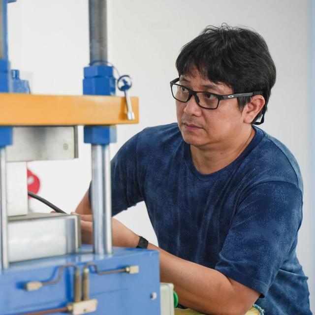 Man in glasses inspecting industrial equipment.