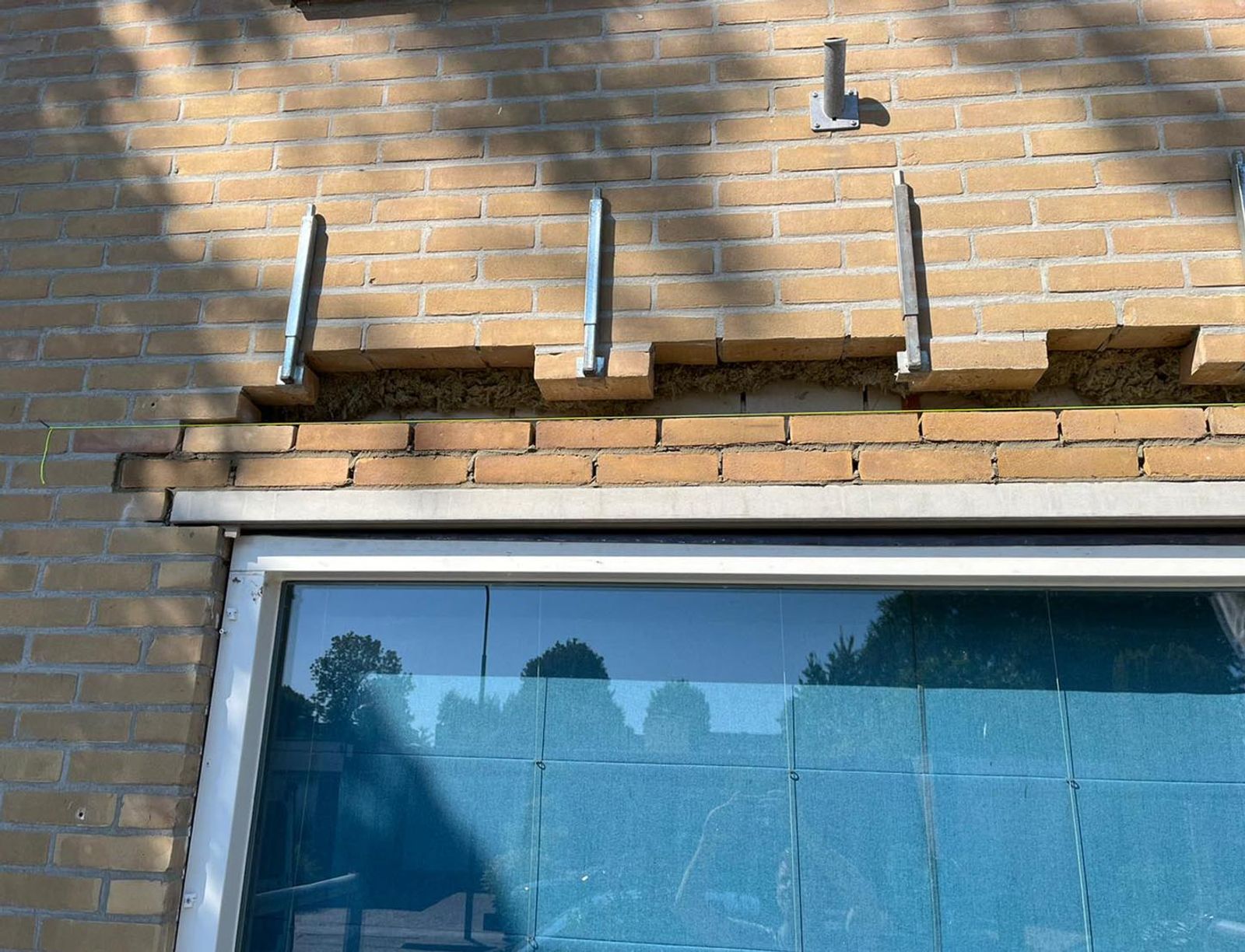 Scheurvorming in metselwerk boven een raamopening door een roestende latei