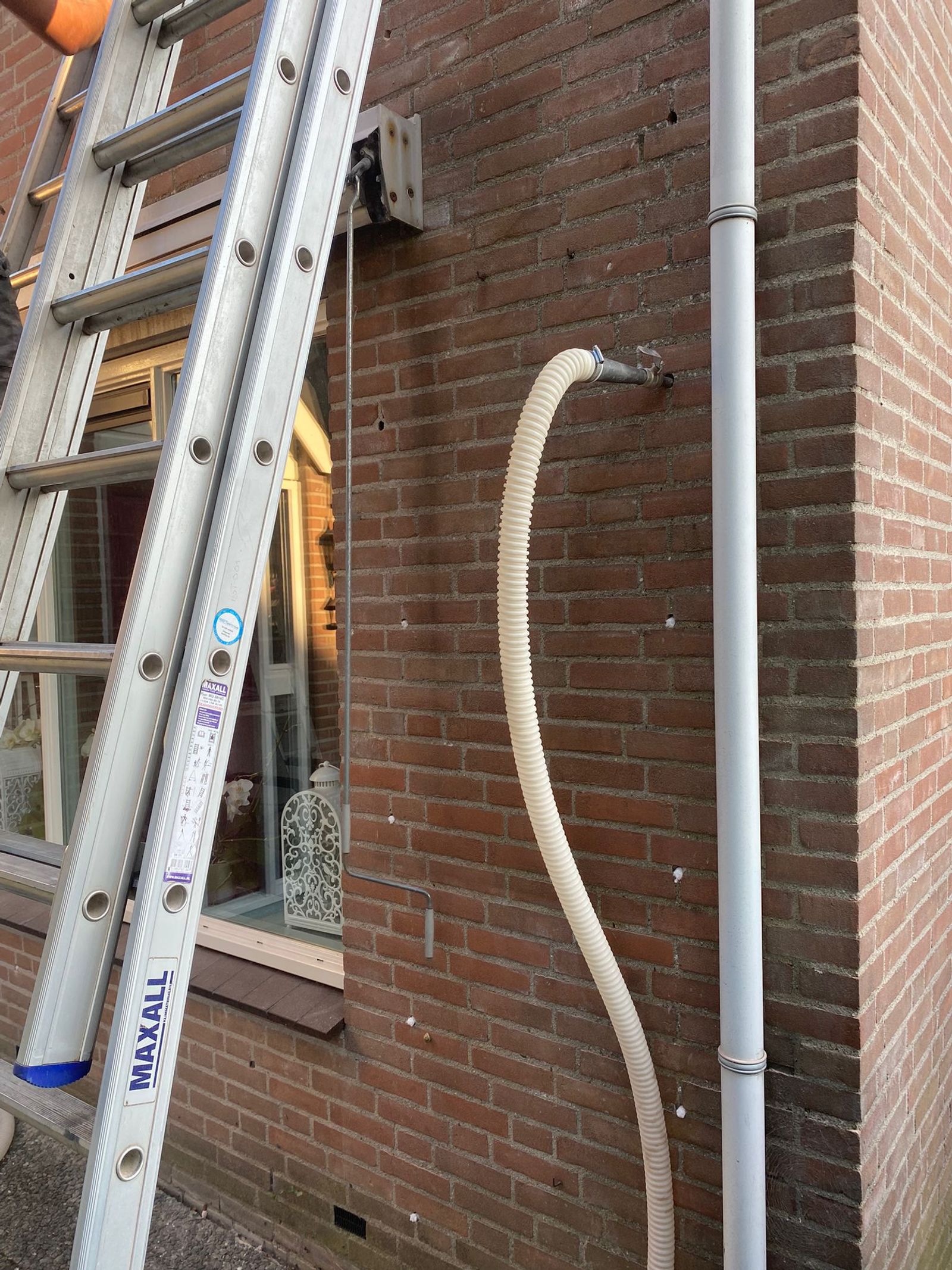 Vakman injecteert isolatieparels in de spouwmuur van een bakstenen gevel