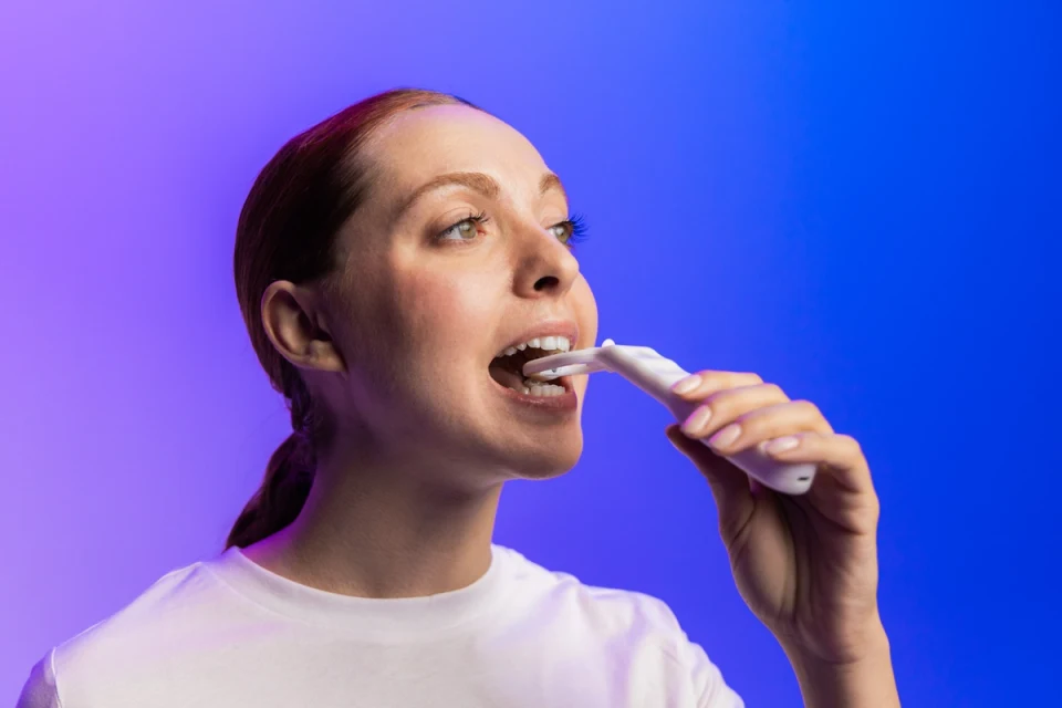Donna utilizza Opendent Plaque Detector su uno sfondo illuminato blu e viola