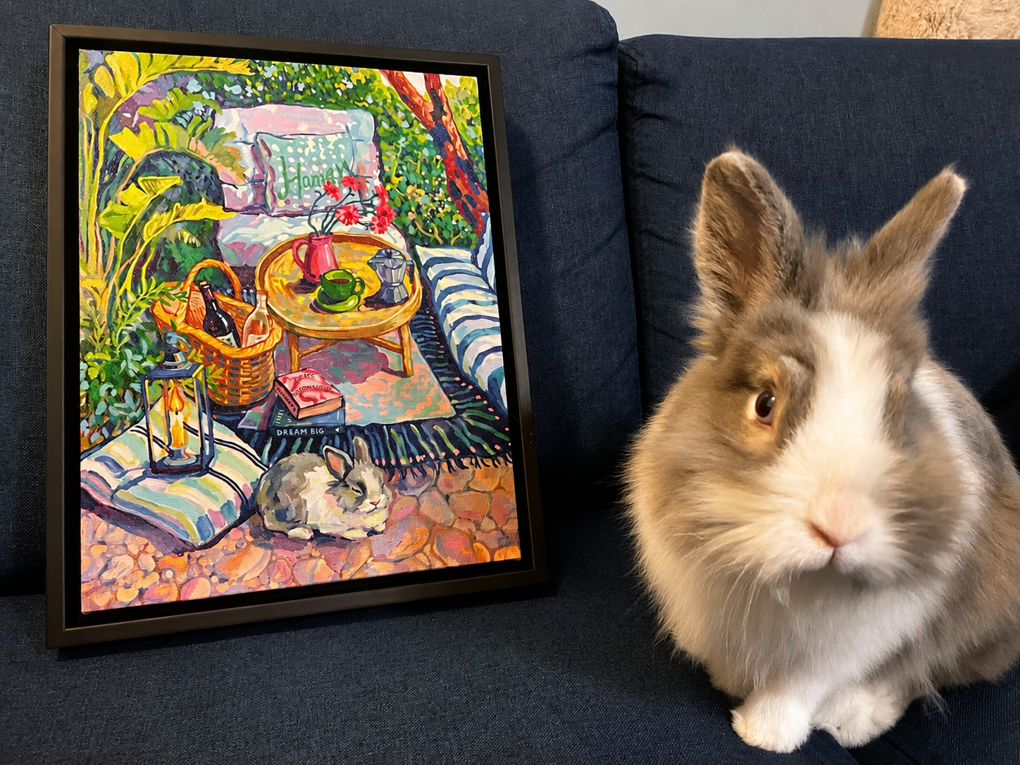 Rabbit beside a framed custom impressionist pet portrait in a colorful garden scene