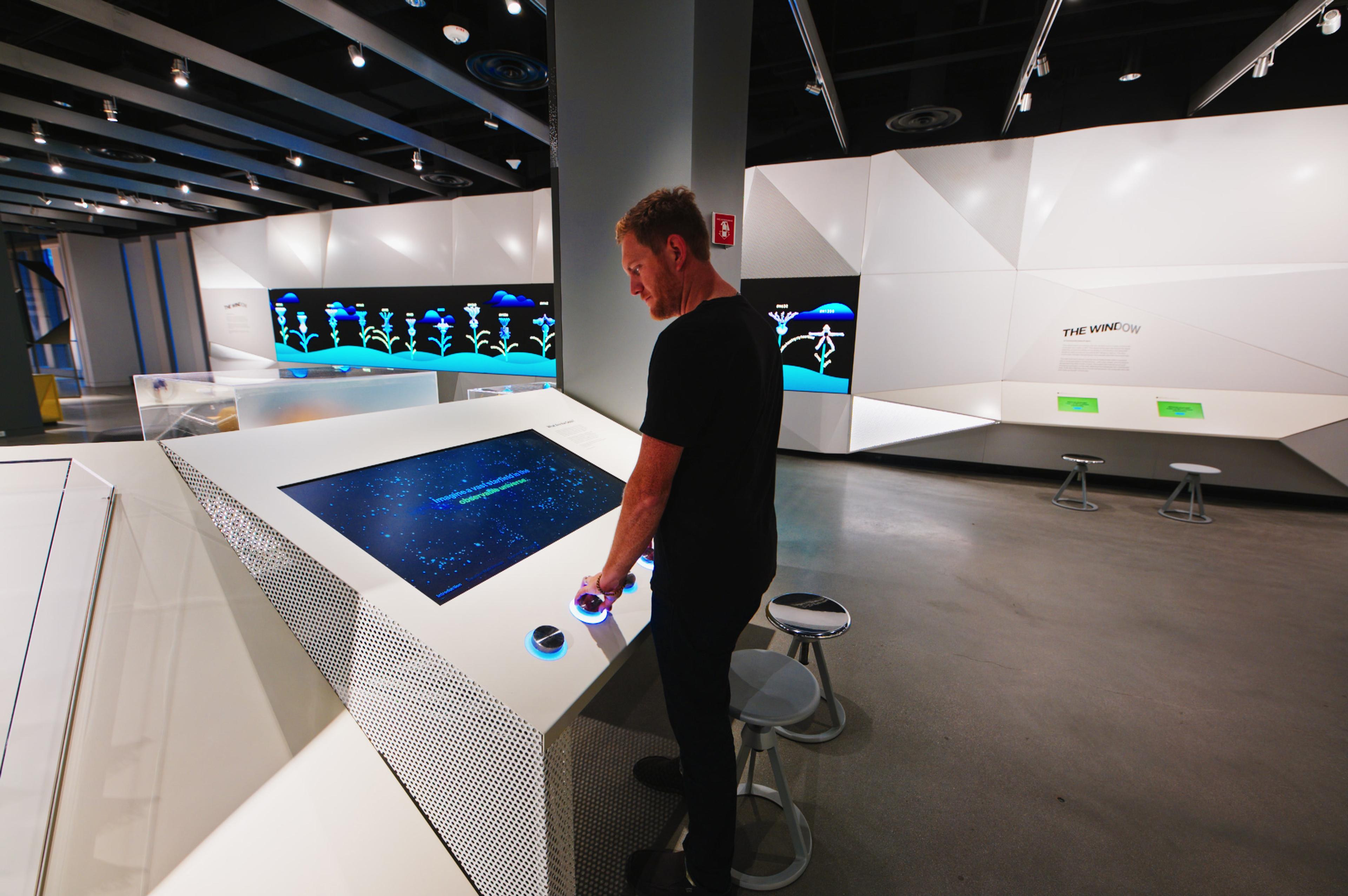 Visitors adjust LED-lit knobs to explore the Sara Seager Equation, predicting extraterrestrial life with a dynamic starfield illustrating results.