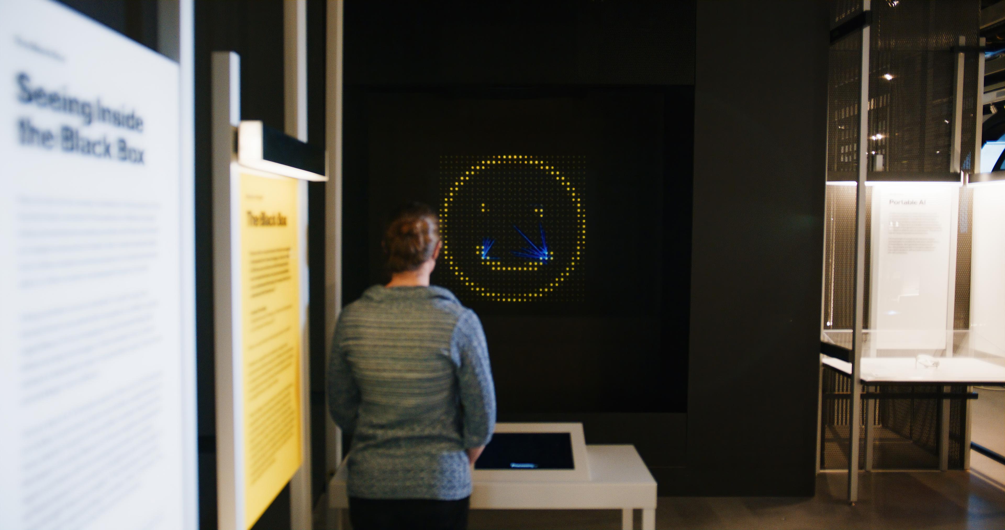 Visitors draw faces on a touchscreen, which are analyzed by AI and displayed in a holographic projection, showing the emotions detected.