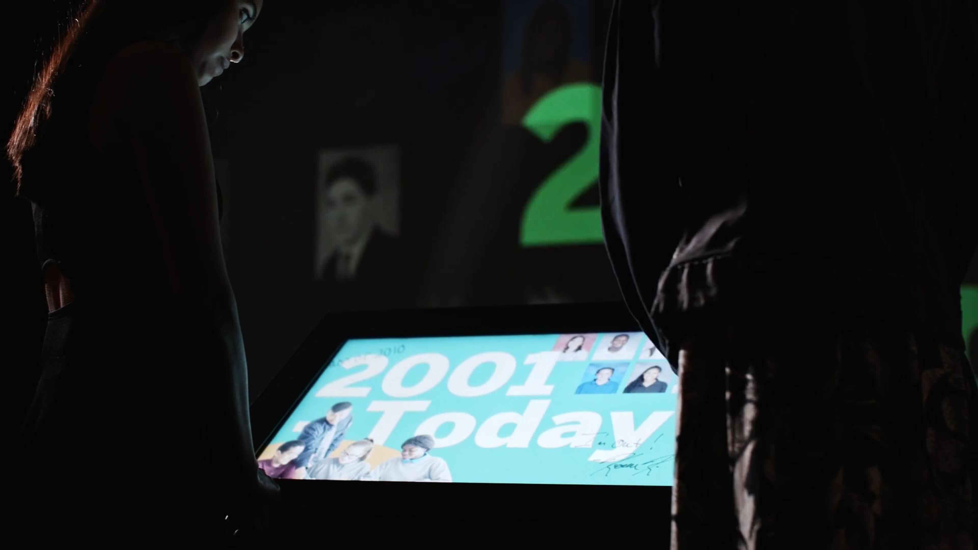 An interactive yearbook uses a touch screen and digital projection to explore the school’s history. The wall projection responds to touch screen input, aligning animations with detailed content.