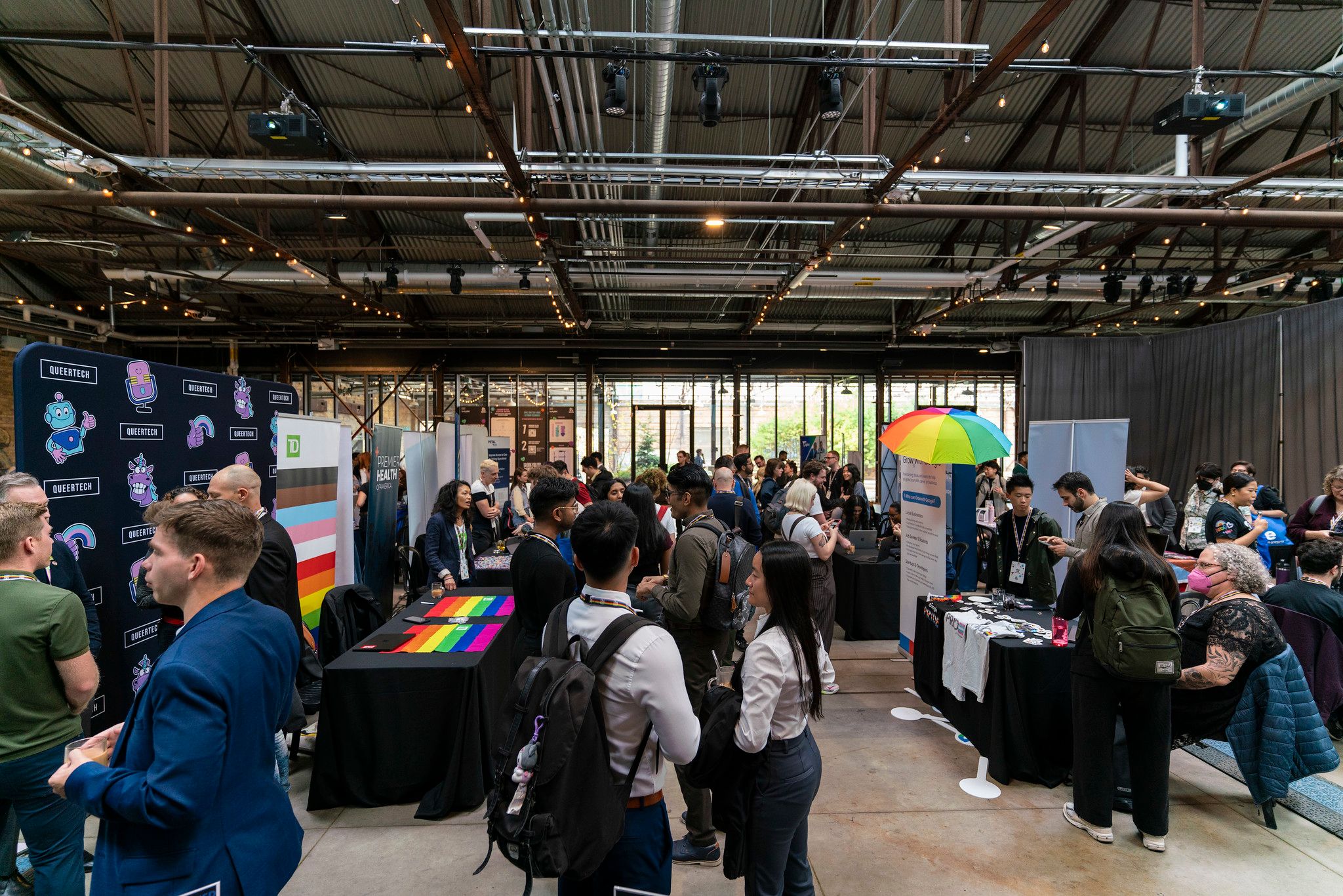 Espace d’exposition et de réseautage animé, avec des participant·e·s visitant des kiosques et échangeant avec des organisations.