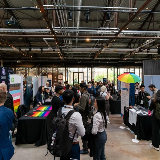 Espace d’exposition et de réseautage animé, avec des participant·e·s visitant des kiosques et échangeant avec des organisations.