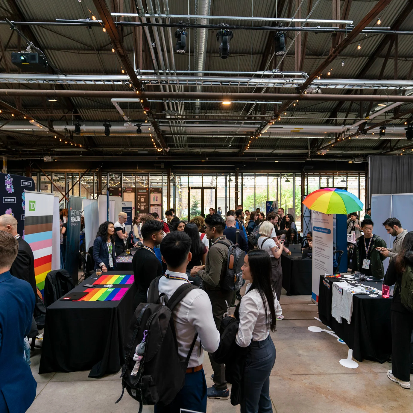 Espace d’exposition et de réseautage animé, avec des participant·e·s visitant des kiosques et échangeant avec des organisations.