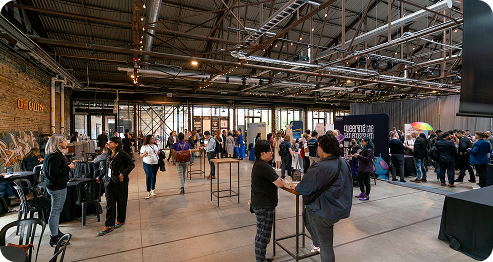 A group of people stands together in a spacious room, engaged in conversation and interaction.