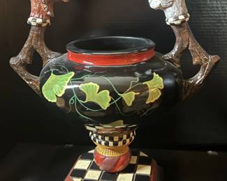 Decorative black urn with painted leaf design, red rim, branch-style handles, and checkered base, featured in a Beverly Hills estate sale.