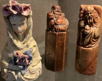 Three small carved and ceramic Asian-style figures displayed together, featured among global collectibles in a Beverly Hills estate sale.