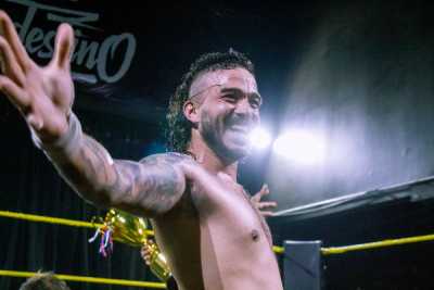Axel sonriendo con los brazos abiertos arriba del ring