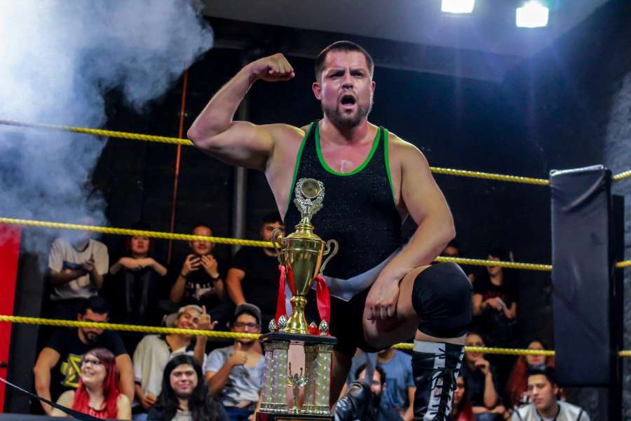 Engranaje posando en el ring junto a la copa tras ganar el Torneo Peso Pesado 2018