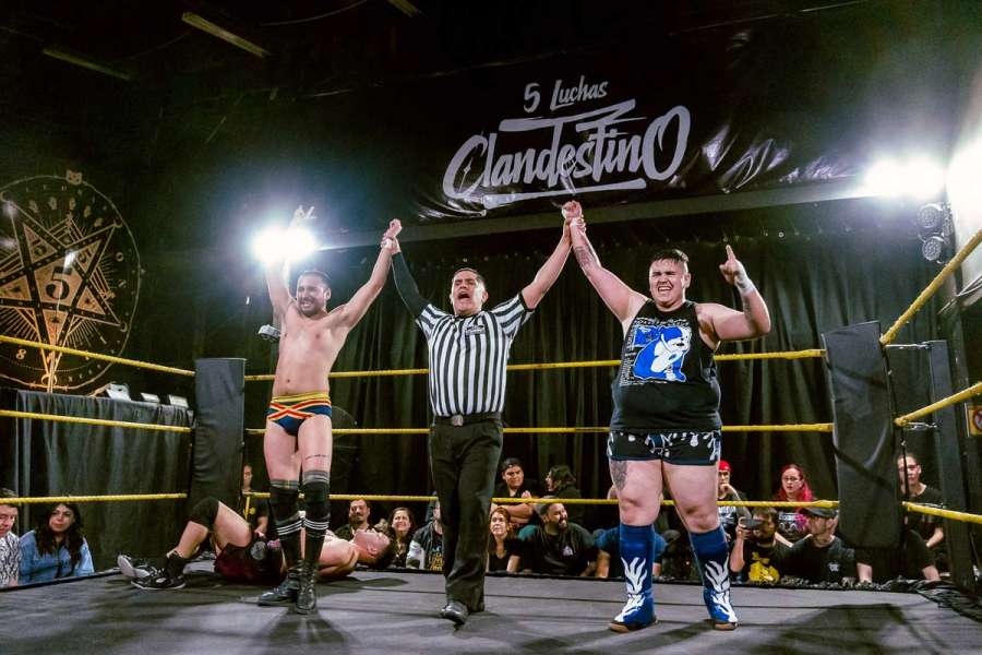 Cooper y Bulldog ganadores de la lucha, Ivan Navarro levantando sus brazos en el centro del ring-