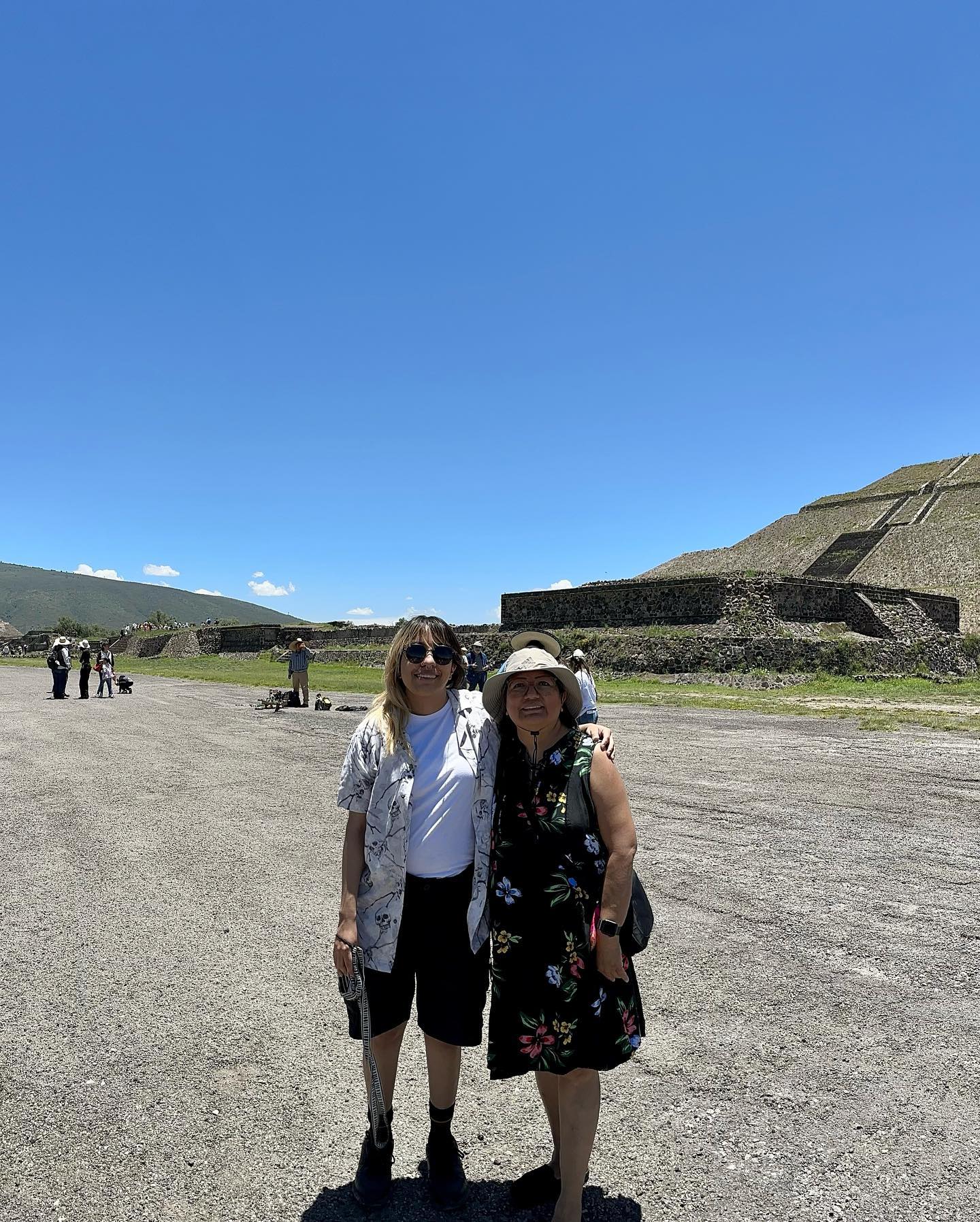 Claudia and T stand in front of a pyramid on a day with clear blue skies.