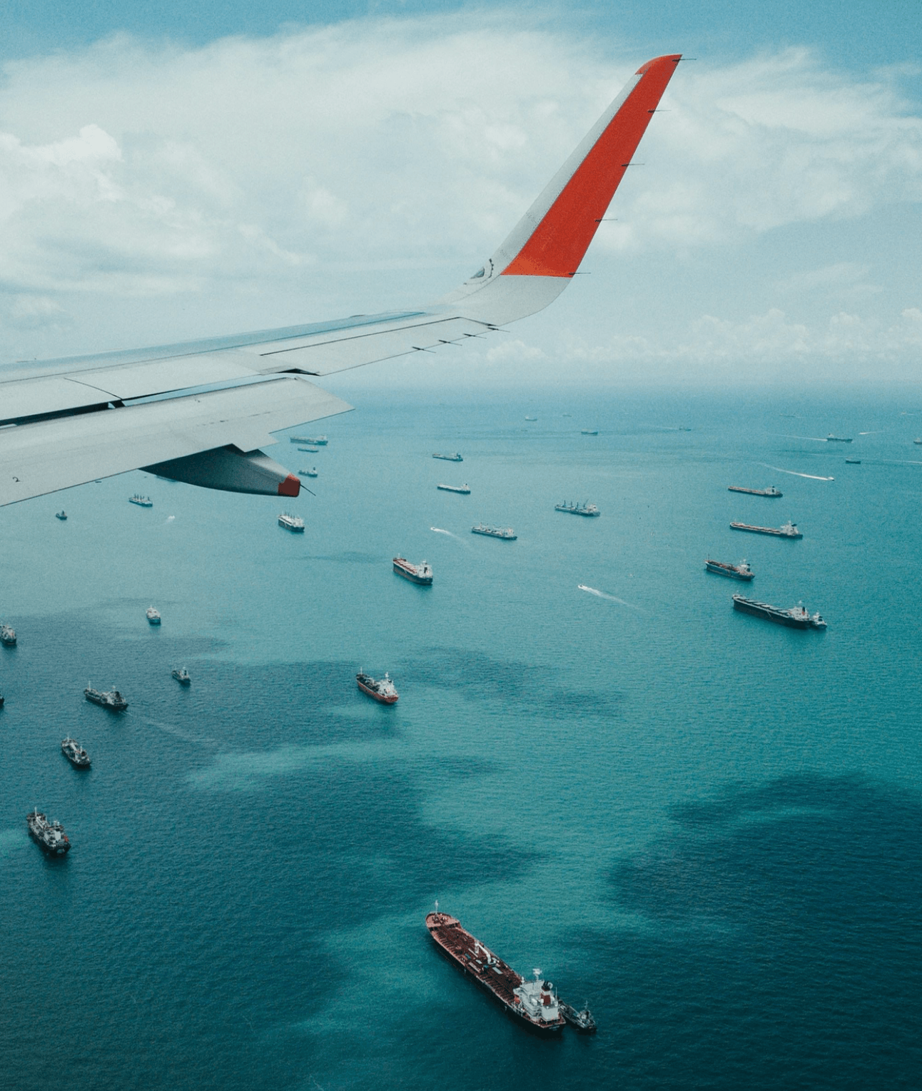 A plane flies of container ships in the ocean