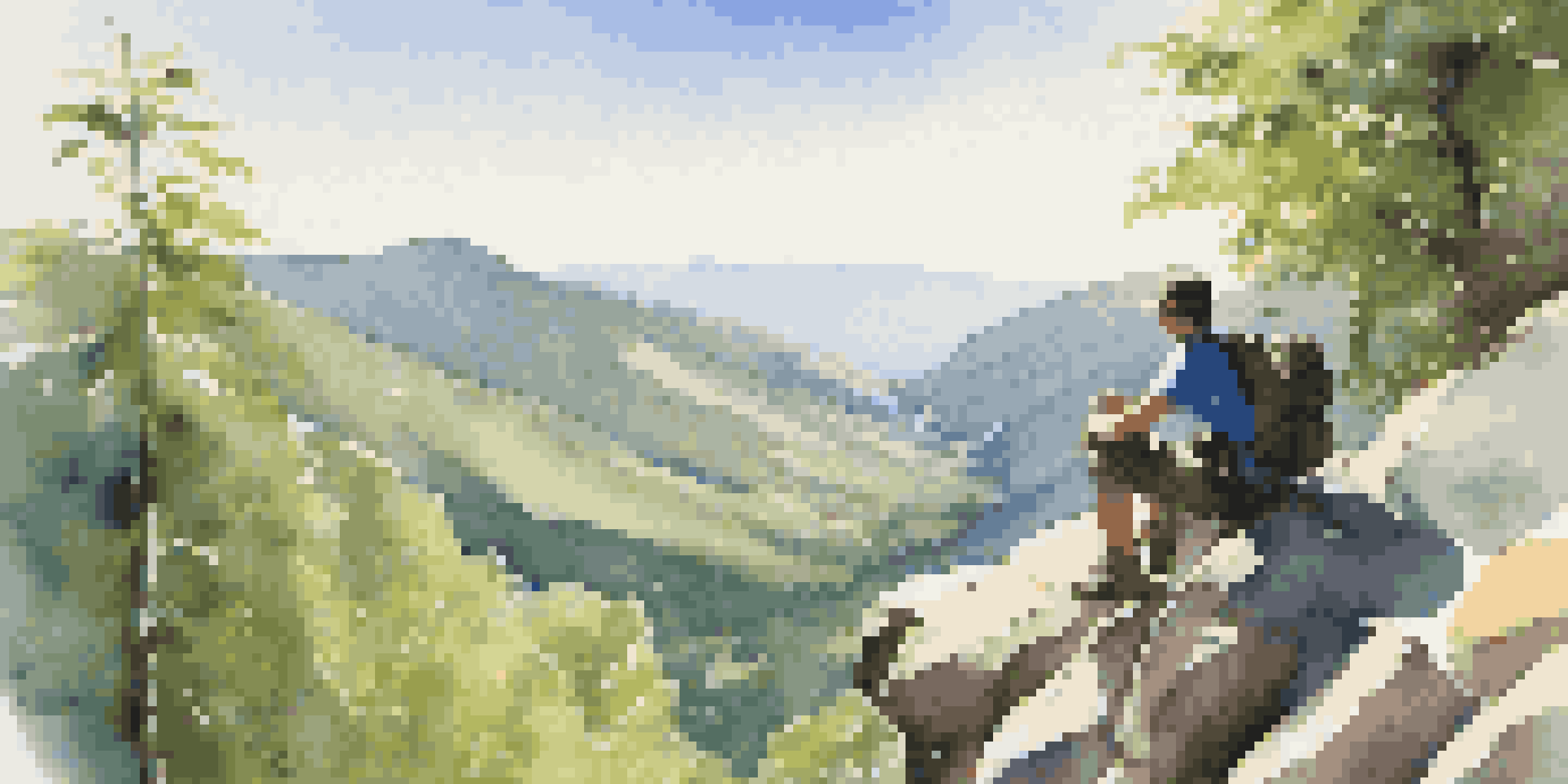 A hiker resting on a rocky ledge in a lush mountain landscape, enjoying the view while drinking water.