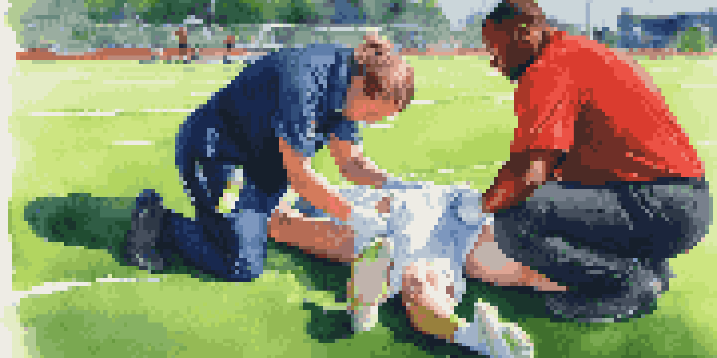 An athletic trainer applying ice to a young athlete's sprained ankle on a sports field, with teammates showing support.