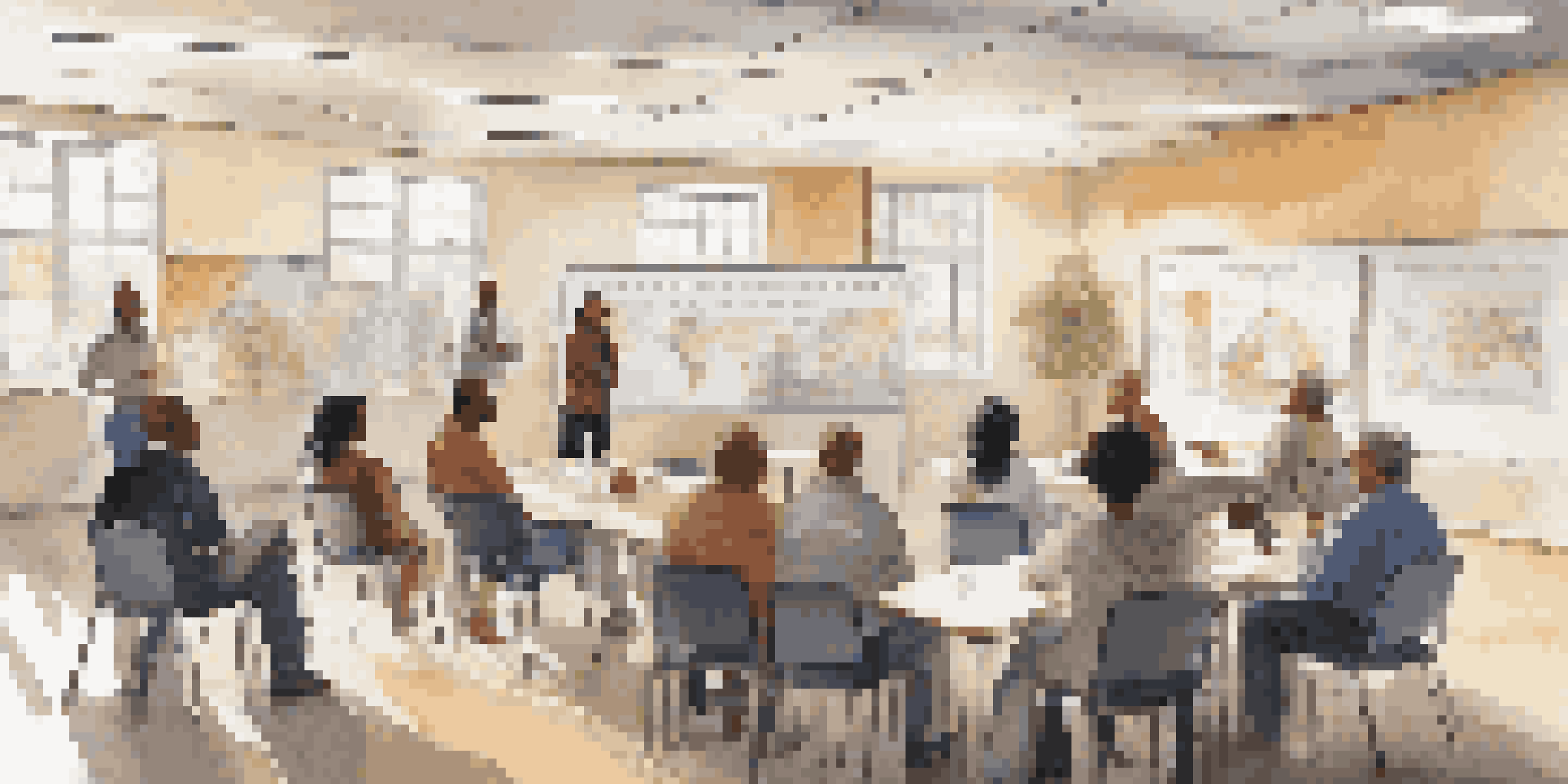 A diverse group of people gathered in a room discussing crisis management, with sunlight streaming through windows and notes on the whiteboard.
