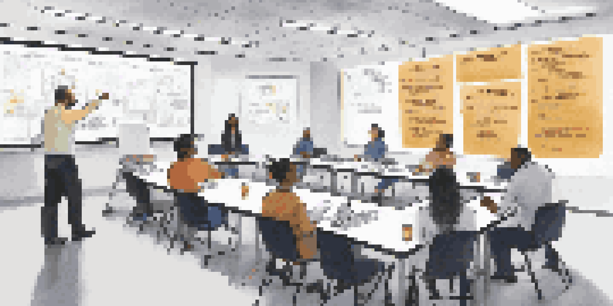 A training room with employees participating in an awareness training session, with a projector screen and safety posters on the walls.