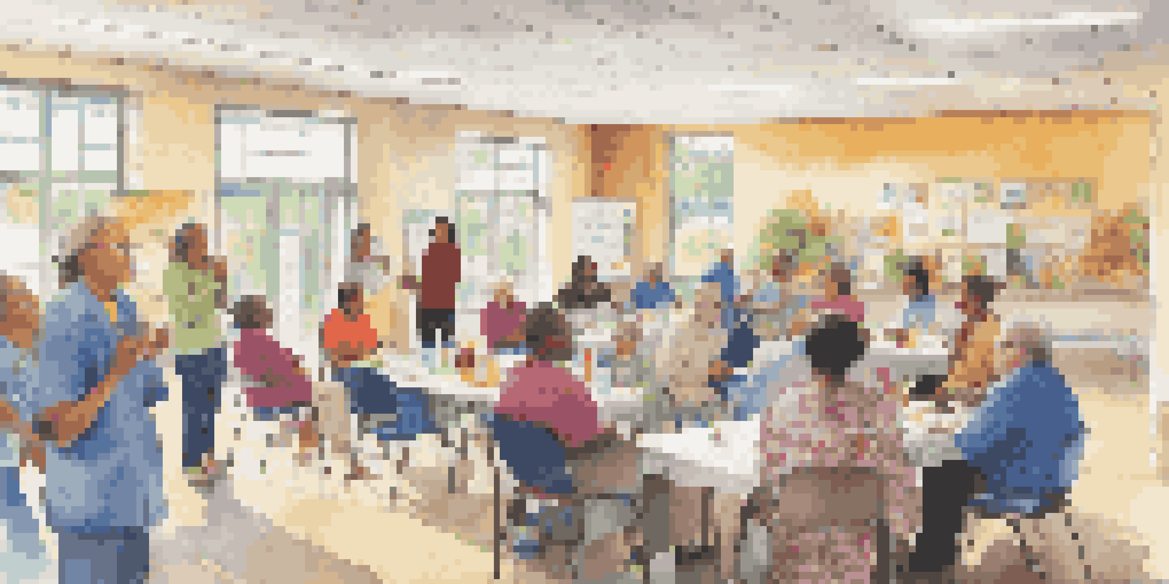 A diverse group of people attending a health workshop in a community center, engaging with educational materials and a healthcare provider.