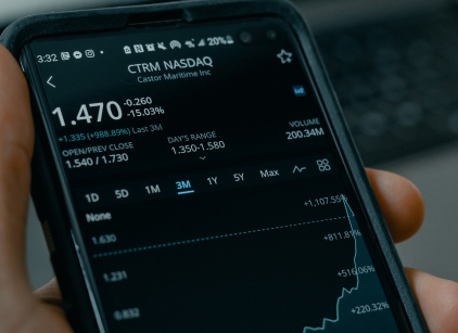 A hand holding a smartphone whose screen shows a line chart, against a softly blurred background.