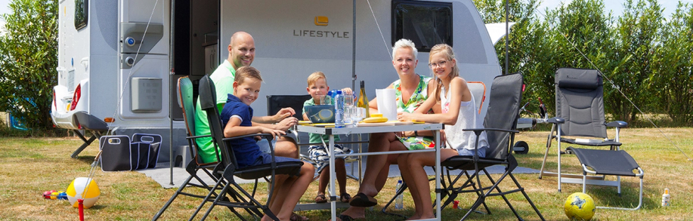 Familie aan tafel voor caravan