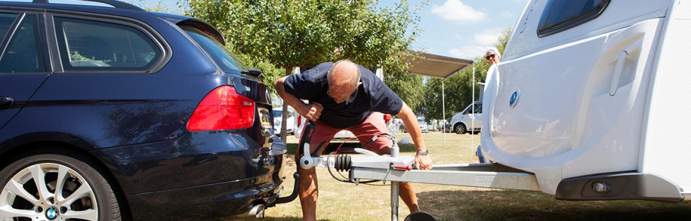 Man die caravan koppelt aan auto 