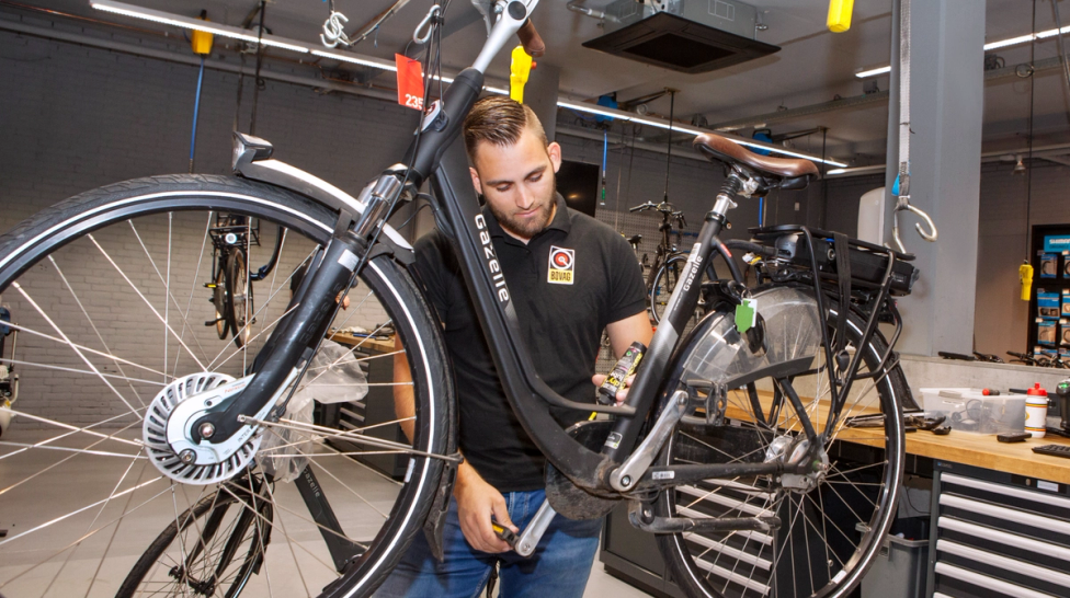 Man met elektrische fiets in werkplaats