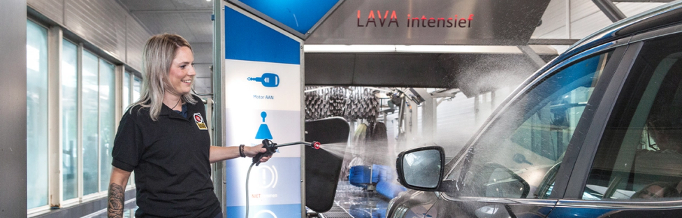 Vrouw in wasstraat, sproeit water op auto