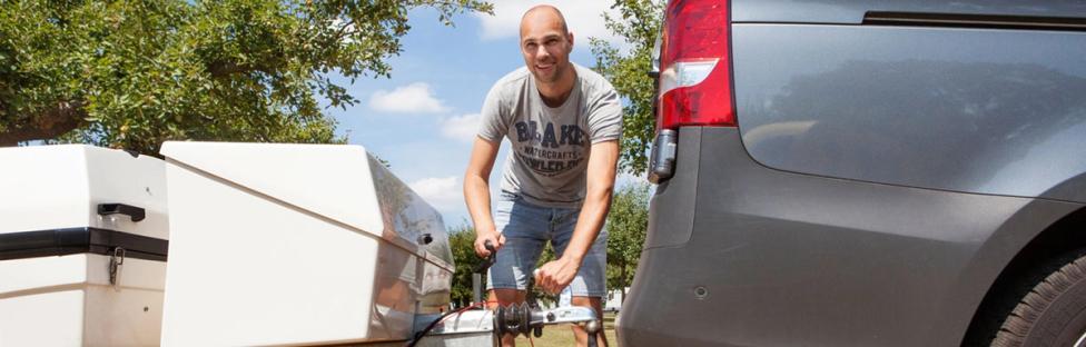 Man die vouwwagen koppelt aan auto