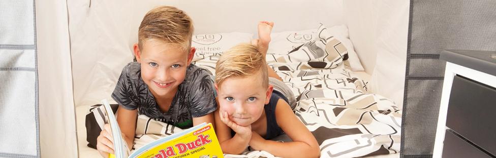Twee kinderen op een bed met tijdschrift