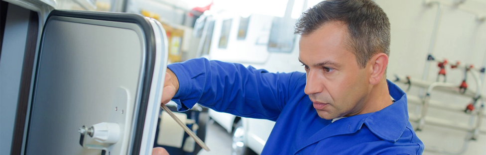 Man sleutelt aan camper deurtje