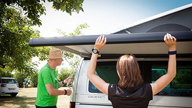 vrouw die zonnescherm uittrekt, man die helpt