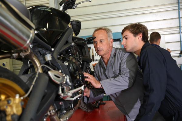 Leerling kijkt mee bij de reparatie van een motor