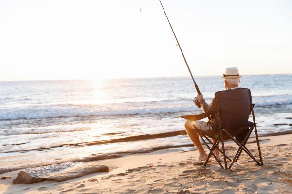 Oudere man aan het vissen op het strand