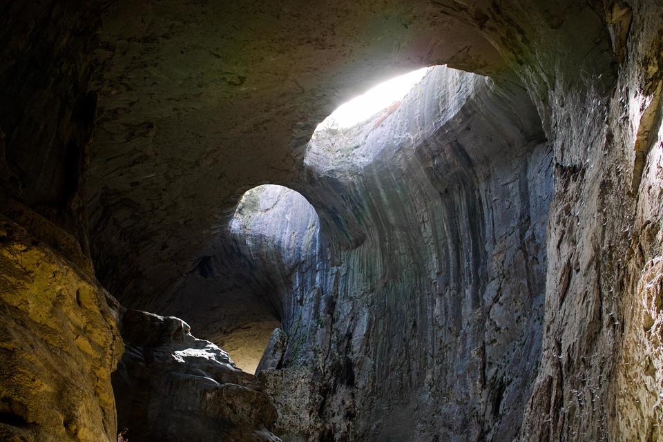 light streaming in through holes in cave ceiling