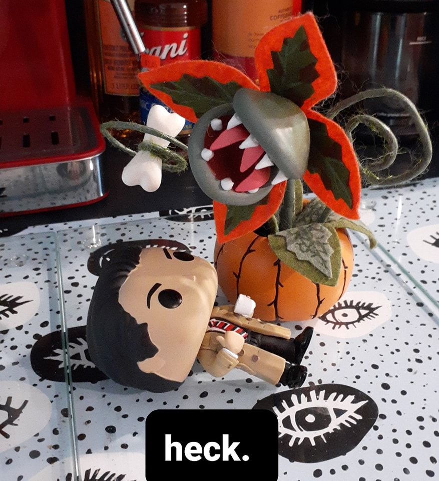 An image with a Funko Pop of Agent Cooper from Twin Peaks laying on the ground with a carnivorous plant looming over him. He is saying "heck".