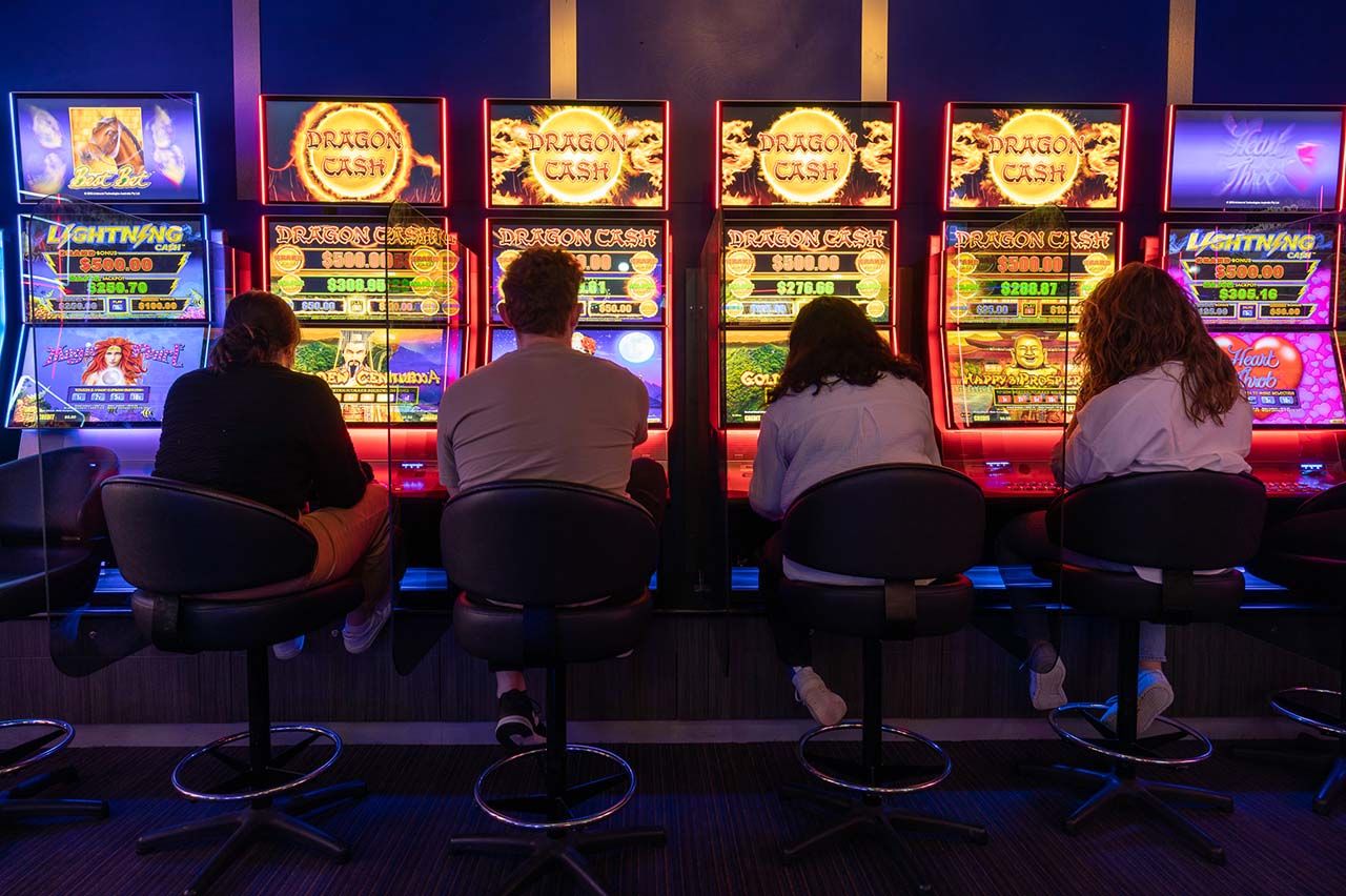 Line up of four people sitting at four pokie machines