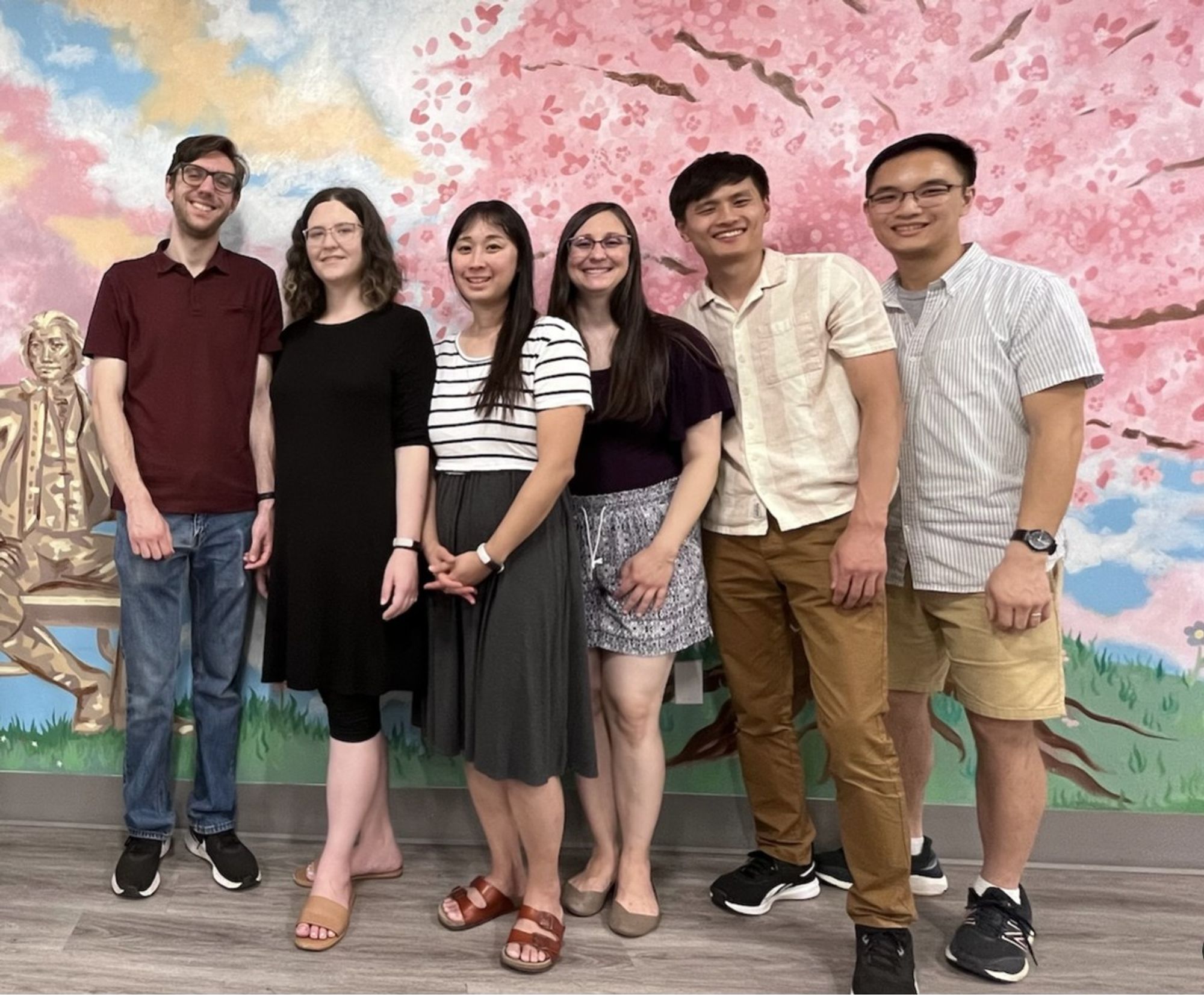 Mentors and students in front of a cherry blossom mural.