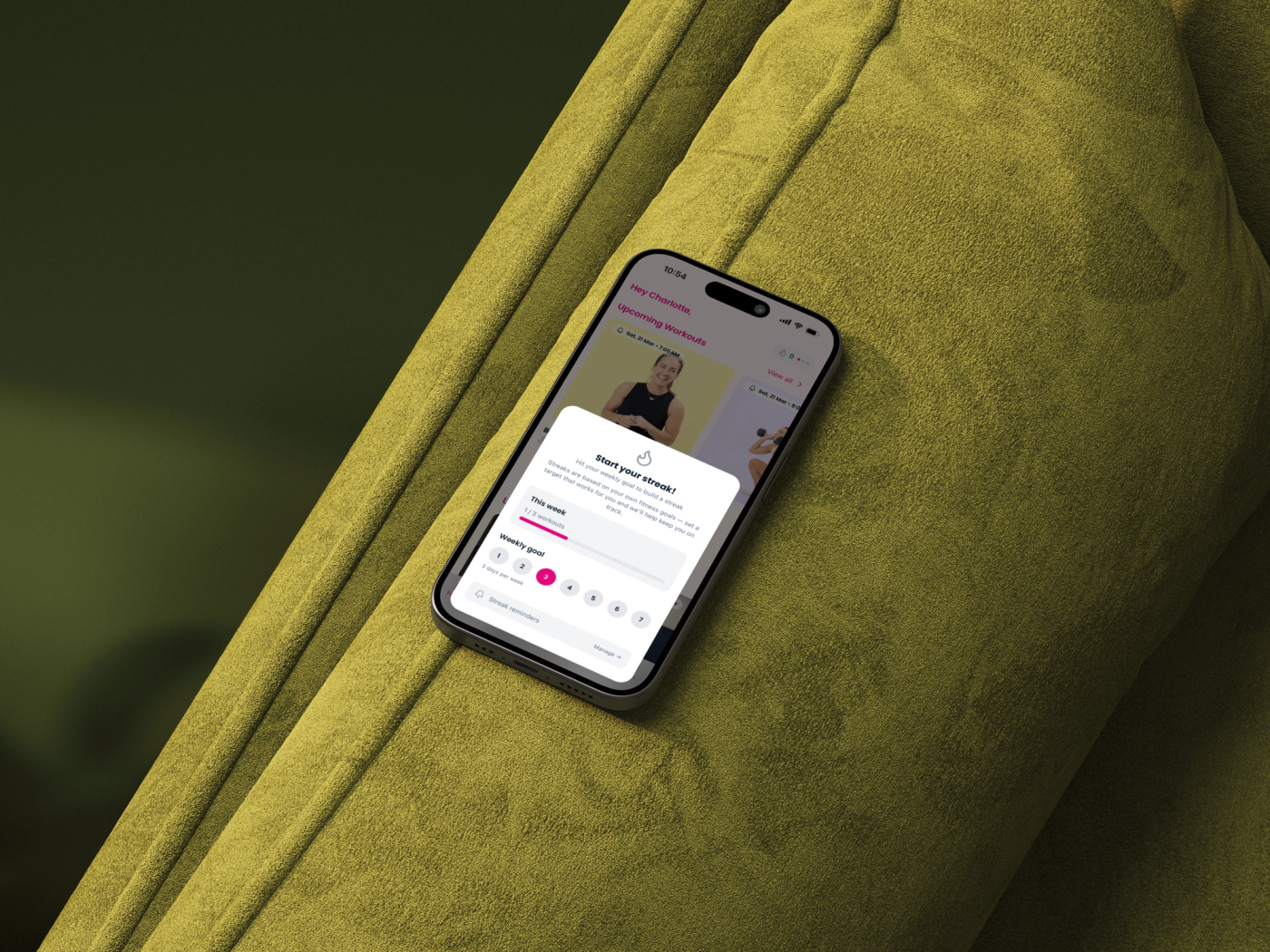 The Move it Mama app on a phone lying on an olive green velvet couch