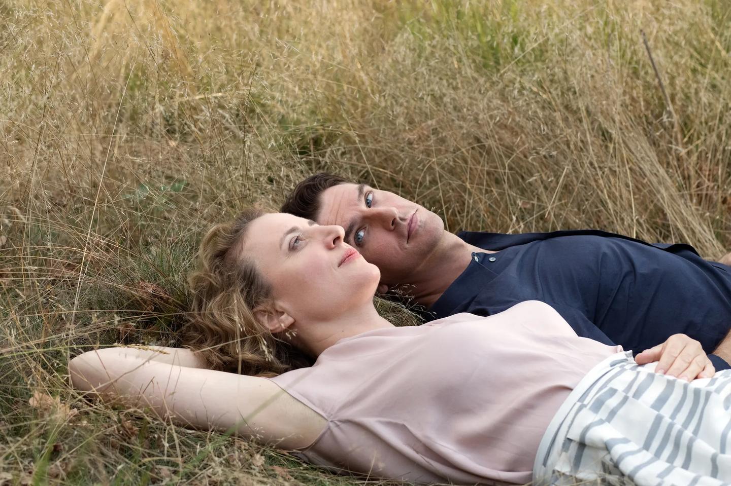 a man and woman lying in the grass