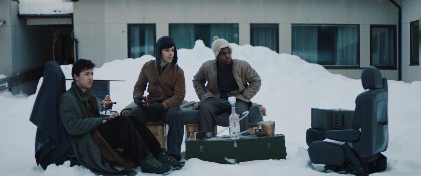 a group of men sitting on a bench in the snow
