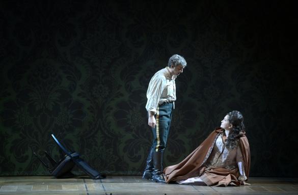 a man standing on a stage with a man sitting on the ground