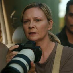 En bekymret Kirsten Dunst holder et kamera foran seg i Civil War.