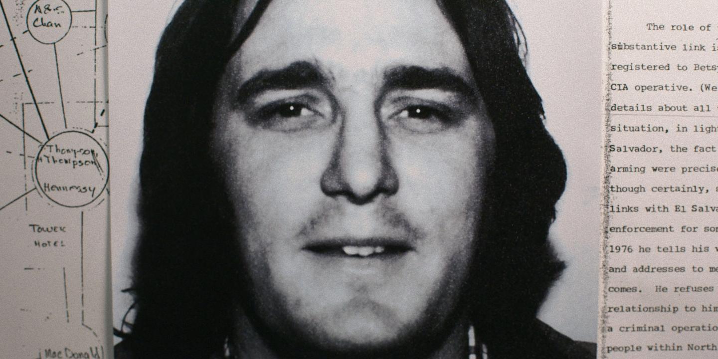 Et bilde av en mann med langt hår ligger oppå andre dokumenter i American Conspiracy: Blekksprutdrapene