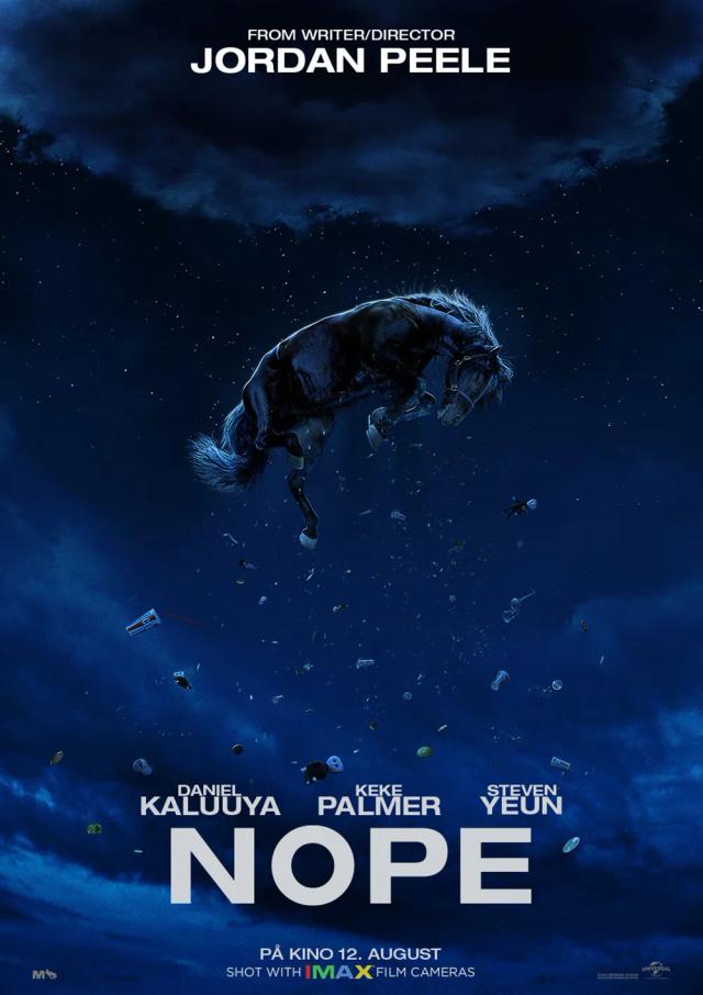 Steven Yeun wearing a hat and holding his hand up in front of a stadium