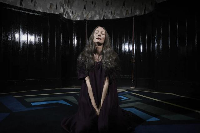 a woman with long hair and a long beard in a dark room
